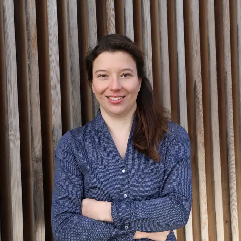 Porträt von Julia Rosendahl, Mitglied der Geschäftsleitung bei PerformaNat, vor einer Holzlamellenwand.
