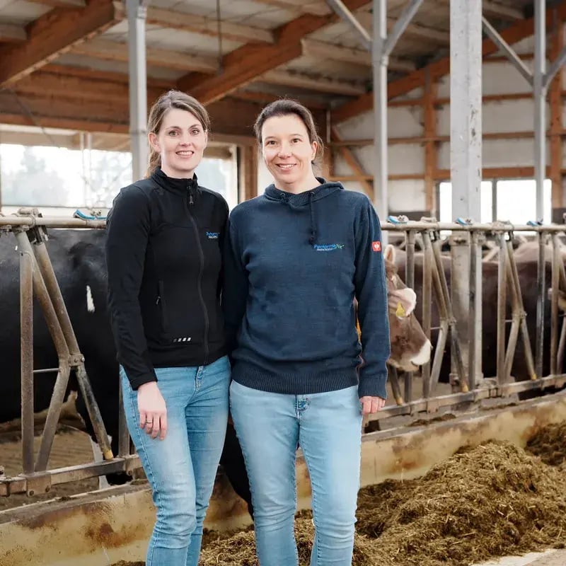 Die PerformaNat-Gründerinnen Katharina Schrapers und Julia Rosendahl stehen lächelnd im Kuhstall. Die PerformaNat-Gründerinnen Katharina Schrapers und Julia Rosendahl stehen lächelnd im Kuhstall.
