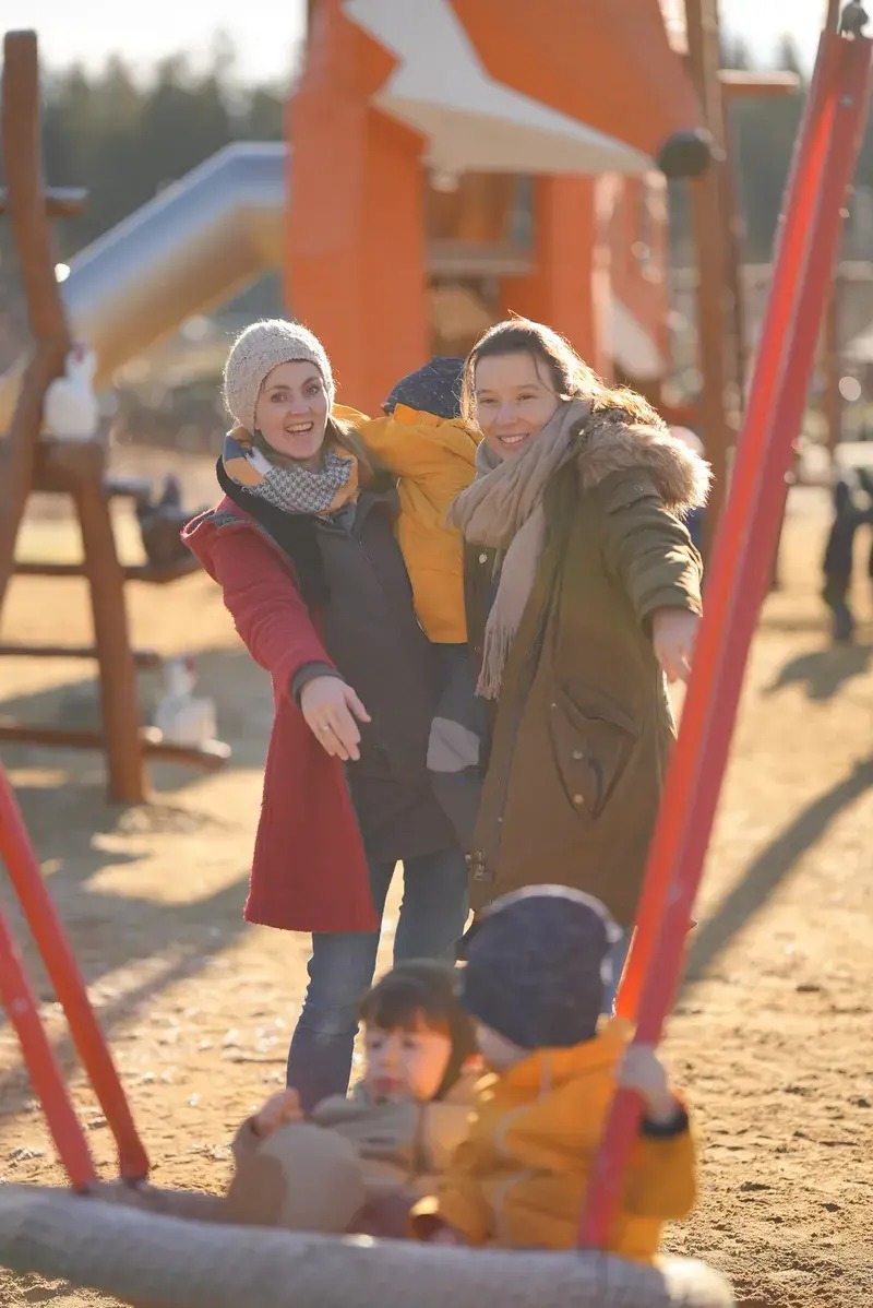 Die PerformaNat-Gründerinnen lachen entspannt mit ihren Kindern auf einem Spielplatz. Familie und Beruf im perfekten Einklang. Die PerformaNat-Gründerinnen lachen entspannt mit ihren Kindern auf einem Spielplatz. Familie und Beruf im perfekten Einklang.